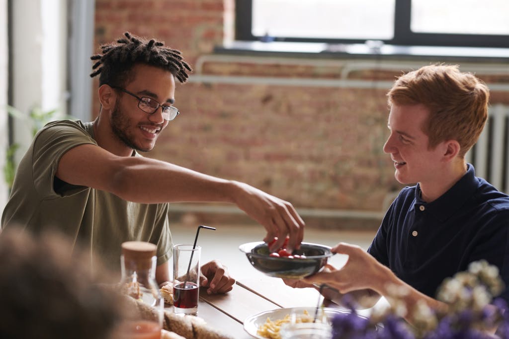 Two friends enjoying a relaxed indoor meal, sharing food and drinks.